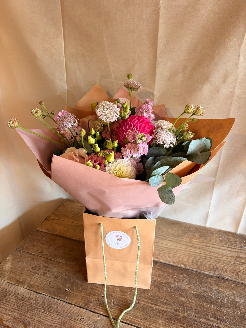 Multi-tonal pink flower bouquet in a kraft gift bag